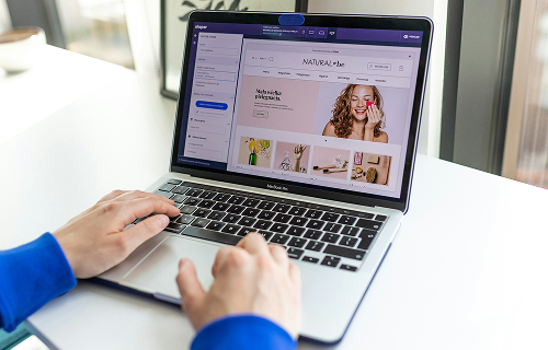 Persona diseñando una tienda en línea desde una laptop, utilizando una plataforma de diseño web con una interfaz gráfica moderna.