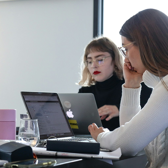Dos personas trabajando con laptops en un entorno de oficina, representando concentración, análisis y desarrollo de proyectos.